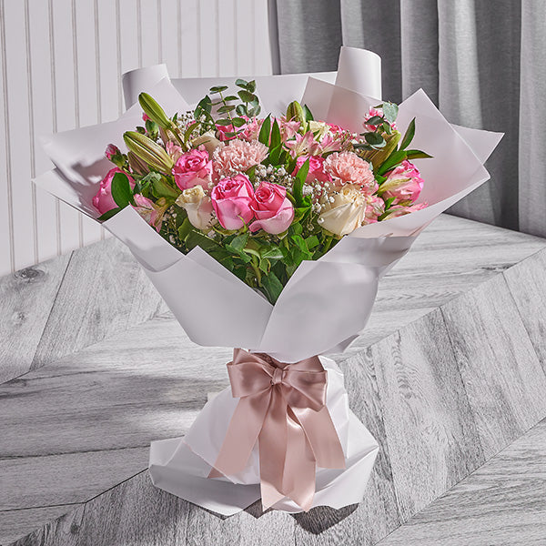 Bouquet of flowers with a pink ribbon on a wooden surface
