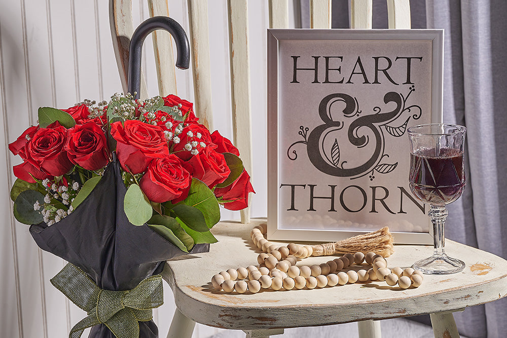 Red rose flower arrangement with heart and thorn picture frame on a chair